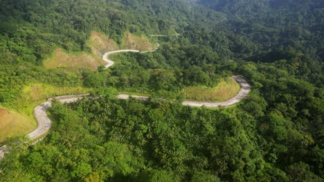 Aerial-Orbit-of-winding-roads-cutting-across-lush-greenery-of-jungle-covered-hills-in-tropical-island-of-Catanduanes,-Philippines