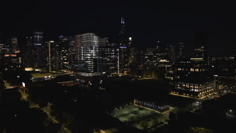 Drone-shot-over-the-Fulton-River-district,-toward-night-lit-skyscrapers-of-Chicago,-USA