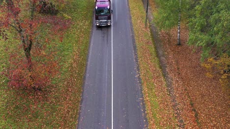 MAN-dump-truck-drive-on-wet-country-road,-aerial-drone-view