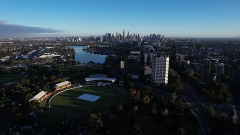 Scenic-aerial-forward,-metropolis-Melbourne-skyline-in-Sunset,-blue-sky,-drone