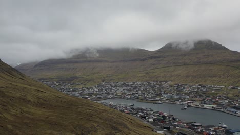 Ascending-aerial-shot-Klaksvik-town-on-Borðoy-surrounded-by-hills,-Faroe-islands