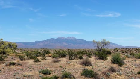 Drohne-Schoss-Rückwärts-über-Die-Trockene-Prärie-Von-Arizona-Mit-Den-Vier-Gipfeln-Im-Hintergrund