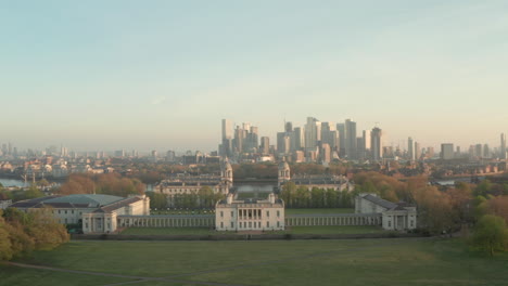 Toma-Aérea-Sobre-El-Museo-Marítimo-De-Londres,-A-Través-De-La-Universidad-De-Greenwich-Hacia-Canary-Wharf-Al-Amanecer.