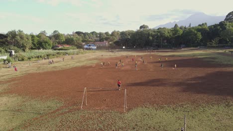 Local-African-teams-play-football-on-arid-pitch-by-Mount-Kilimanjaro,-Loitokitok,-Kenya
