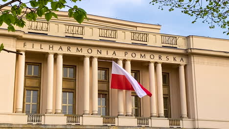 Das-Gebäude-Der-Pommerschen-Philharmonie-In-Bydgoszcz-Mit-Einer-Riesigen-Polnischen-Flagge,-Die-über-Dem-Haupteingang-Des-Gebäudes-Weht