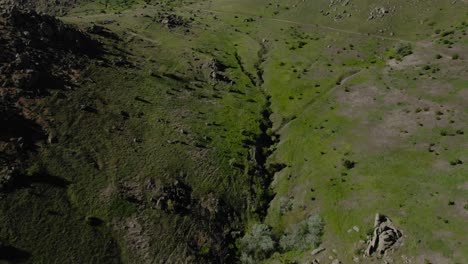 Aufschlussreiche-Luftaufnahme-Einer-Alten-Erodierten-Bergkette-über-Einer-Kurvenreichen-Straße-An-Einem-Sonnigen,-Klaren-Tag