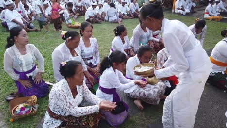 Female-Priestess-dressed-all-white-blesses-with-holy-water-Balinese-Hindu-Believers-in-a-Religious-Temple-Ceremony-of-Bali-Indonesia