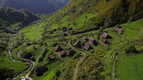 Cinematic-tilt-up-view-of-a-remote-village-with-several-thatched-huts-on-the-valley-slope