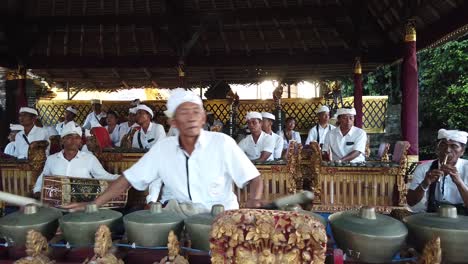 Ein-älterer-Mann-Mit-Weißen-Haaren-Spielt-Mit-Seinem-Orchester-Traditionelle-Asiatische-Percussion-Musik-Gamelan-Bei-Einer-Tempelzeremonie-Auf-Bali,-Indonesien