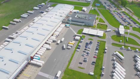 Time-lapse-Logistics-park-with-warehouse,-loading-hub-and-many-semi-trucks-with-cargo-trailers-standing-at-the-ramps-for-load-unload-goods