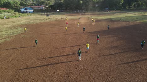 African-teams-play-football-match-on-arid-pitch-in-Loitokitok,-Kenya,-aerial