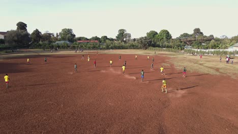 African-teams-playing-soccer-on-arid-football-pitch-in-Loitokitok,-Kenya,-aerial