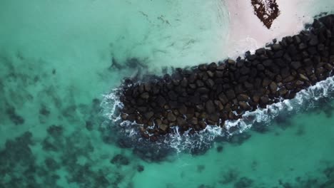 Top-down-aerial-view-of-waves-crashing-on-rocks-in-the-ocean-in-Barbados