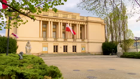 Das-Gebäude-Der-Pommerschen-Philharmonie-In-Bydgoszcz-Mit-Einer-Riesigen-Polnischen-Flagge,-Die-über-Dem-Haupteingang-Des-Gebäudes-Weht,-Herauszoomen