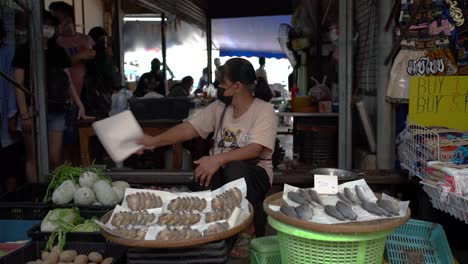 Los-Vendedores-Venden-Pescado-Y-Esperan-A-Los-Clientes-En-El-Mercado-Ferroviario-De-Maeklong,-Una-Atracción-única-Y-Fascinante-En-La-Provincia-De-Samut-Songkhram,-Al-Suroeste-De-Bangkok,-Tailandia