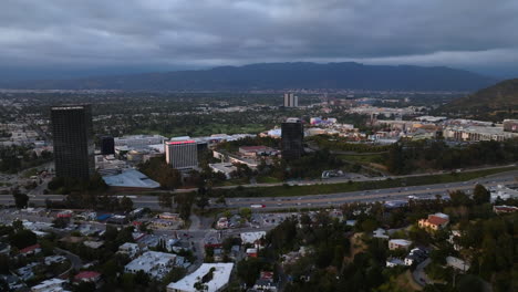 Aerial-view-approaching-the-Universal-City,-cloudy-evening-in-San-Fernando-Valley,-LA,-USA
