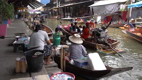 Vendors-operating-their-boats-and-selling-their-products-directly-to-tourists-in-Damnoen-Saduak-Floating-Market,-Ratchaburi-province,-South-West-of-Bangkok,-Thailand