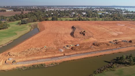 Yarrawonga,-Victoria,-Australia---18-April-2023:-Aerial-pullback-from-working-excavator-revealing-golf-course-and-Lake-Mulwala-with-Yarrawonga-township-in-the-background