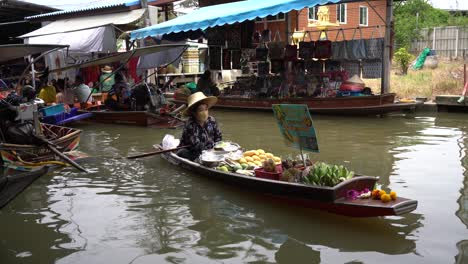 Vendors-sell-fresh-fruits-from-their-boats-in-Damnoen-Saduak-Floating-Market,-the-vibrant-scenery-in-Ratchaburi-province,-South-West-of-Bangkok,-Thailand