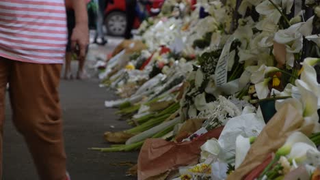 People-walking-past-the-wall-of-flowers-near-school-shooting-Belgrade,-Serbia