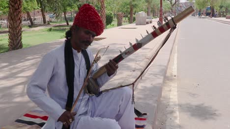 Mann-Spielt-Traditionelles-Musikinstrument-In-Authentischer-Lokaler-Kleidung-Auf-Der-Straße-Von-Indien-Am-Morgen.-Das-Video-Wurde-Am-11.-April-2023-In-Jodhpur,-Rajasthan,-Indien,-Aufgenommen