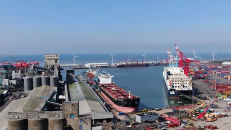 Container-ships-and-cranes-in-the-Royal-Seaforth-dock-on-the-river-mersey-with-wind-turbines-and-steel-terminal-in-background