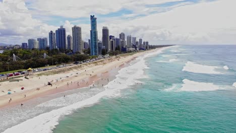 Surfers-Paradise,-Queensland-Australia---February-28-2021:-Aerial-of-Surfers-Paradise-looking-north-with-beach-goers-and-swimmers-in-the-waves