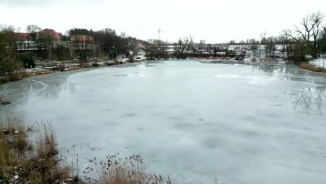 Eiskalter-See-In-Einem-Stadtpark-Mit-Einer-Belebten-Straße-Im-Hintergrund