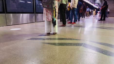 Passagiere,-Die-Abends-An-Der-U-Bahn-Station-Aus-Niedrigem-Winkel-Auf-Die-U-Bahn-Warten.-Das-Video-Wurde-Am-10.-April-2022-An-Der-U-Bahn-Station-Hauz-Khas-In-Neu-Delhi,-Indien,-Aufgenommen