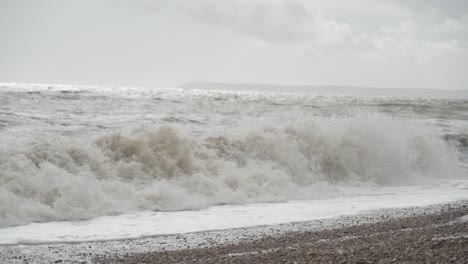 Sea-waves-crashing-onto-pebble-beach-on-a-cloudy-day-in-Hastings,-England