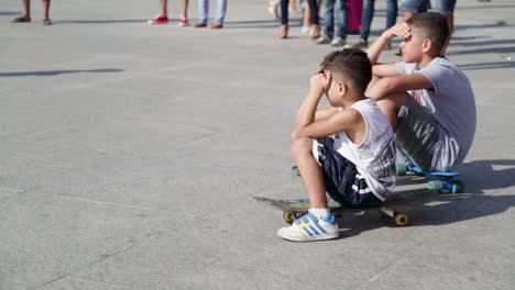 Jungen-Sitzen-Auf-Einem-Skateboard-Und-Schauen-Sich-Eine-Straßenaufführung-In-Rio-De-Janeiro,-Brasilien-An