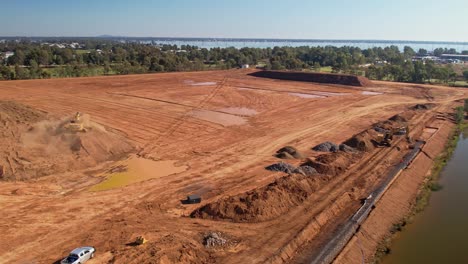 Yarrawonga,-Victoria,-Australia---18-April-2023:-Aerial-view-of-tracked-excavator-unloading-dirt-with-reveal-of-building-site-at-Yarrawonga