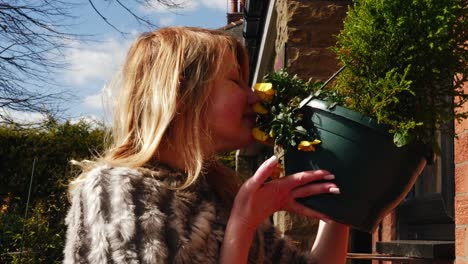 Happy-woman-enjoying-scent-basket-of-flowers-in-garden-medium-portrait-zoom-shot-slow-motion-portrait