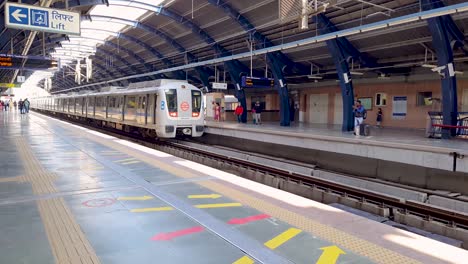 Tren-De-Metro-Llegando-A-La-Estación-Con-Pasajeros-Esperando-Para-Abordar-El-Video-Fue-Tomado-En-La-Estación-De-Metro-Jankpuri-West-Nueva-Delhi-India-El-10-De-Abril-De-2022