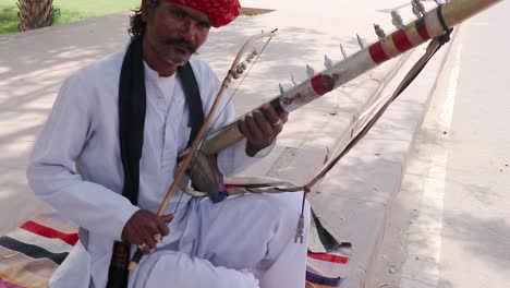 Mann-Spielt-Traditionelles-Musikinstrument-In-Authentischer-Lokaler-Kleidung-Auf-Der-Straße-Von-Indien-Am-Morgen.-Das-Video-Wurde-Am-11.-April-2023-In-Jodhpur,-Rajasthan,-Indien,-Aufgenommen
