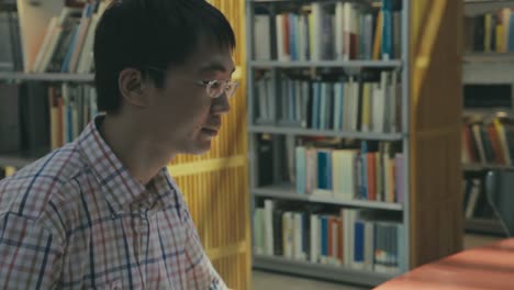 Asiatischer-Student,-Der-An-Einem-Computerterminal-In-Der-Bibliothek-Arbeitet,-Um-Zu-Studieren-Und-Zu-Forschen