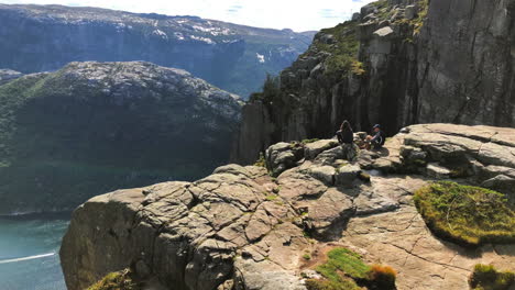 Two-tourists-conversing-on-the-cliff-edge-camp-of-Preikestolen-Pulpit-rock-with-clouds-passing-by