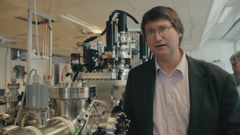 Close-up-interview-with-university-science-professor-with-large-silver-laboratory-equipment-beside-him