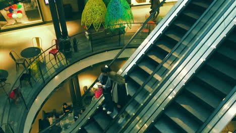 Zwei-Neugierige-Frauen-Schauen-Auf-Einen-Mobilen-Bildschirm-Und-Steigen-In-Einem-Einkaufszentrum-In-Stockholm-Eine-Rolltreppe-Hinunter