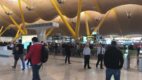 Panorámica-Lenta-A-La-Derecha-De-La-Gente-Caminando-En-Una-Terminal-Del-Aeropuerto-De-Madrid.