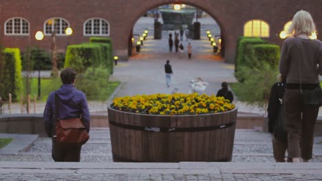 A-large-planter-of-yellow-flowers-decorates-steps-on-a-college-campus-as-students-walk-past