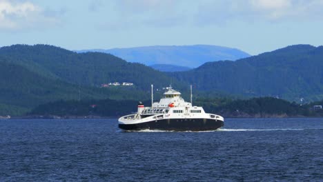 Wide,-scenic-view-of-a-small-passenger-ferry-crossing-a-fjord-in-Norway-with-the-lush-mountain-landscape-on-the-horizon