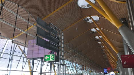High-ceiling-covered-in-wood-and-supported-by-steal-beams-and-concrete-pillars,-T4-terminal-at-Madrid-Barajas-Airport,-modern-construction-and-architecture,-travel-and-transportation-concept