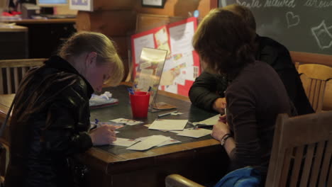A-small-group-of-people-writing-letters-to-Santa-Claus-sit-at-a-table-in-Santa-Claus-Village-in-Finland