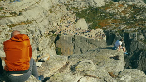 Tourist-couple-reminiscing-memories-on-the-rocky-cliff-of-Preikestolen-Pulpit-Rock-in-Norway