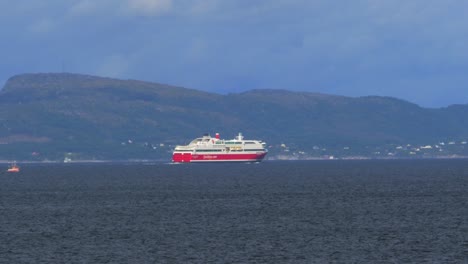 View-from-the-water-of-a-commercial-ferry-transiting-a-Norwegian-fjord-carrying-people,-vehicles-and-supplies-to-another-port