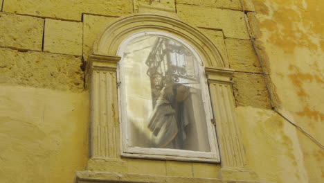 Holy-statue-of-Mary-in-a-glass-box-frame-of-a-church-facade-wall-in-the-day