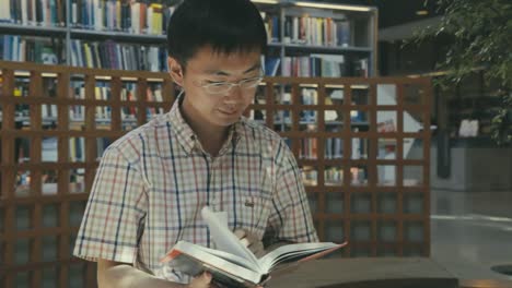 Vista-De-Cerca-De-Un-Joven-Asiático-Leyendo-Un-Libro-En-La-Biblioteca-De-La-Universidad