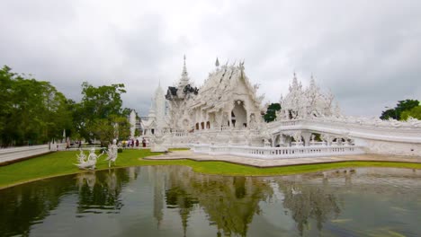 Toma-Panorámica-De-Un-Estanque-Y-El-Templo-Blanco-En-Chiang-Rai,-En-Un-Día-Nublado,-En-Tailandia,-Asia