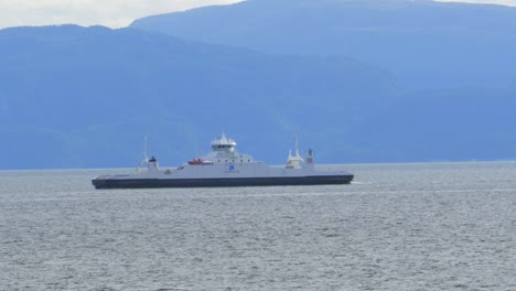 A-large-commercial-ferry-transiting-a-Norwegian-fjord-carrying-people,-vehicles-and-supplies-to-another-port